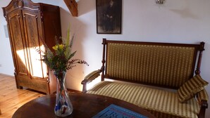 A wooden cabinet, a sofa, a table with a book, and a vase with flowers. - Historic holiday home for families and groups
with garden and play barn. (Janowice Wielkie)