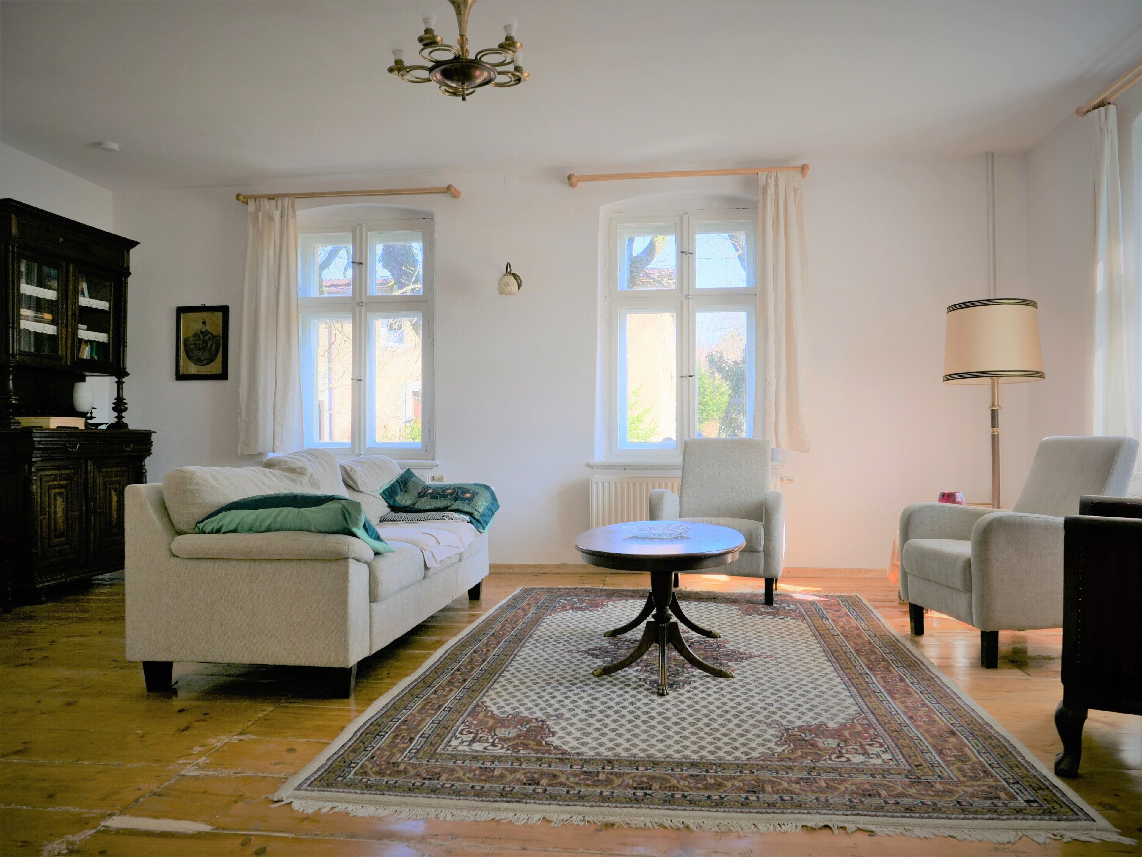 A living room with a sofa, armchairs, a small table, a rug, and a chandelier.