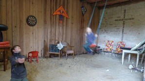 A room with a wooden wall, a dartboard, a Spiderman kite, and a bicycle. - Historic holiday home for families and groups
with garden and play barn. (Janowice Wielkie)
