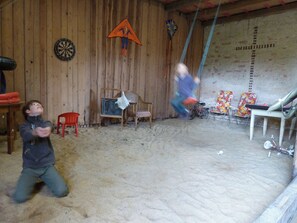 Quarto com parede de madeira, alvo de dardos, pipa do Homem-Aranha e bicicleta.