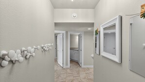 Un couloir doté d’un sol en marbre, de murs blancs et d’une série de portes blanches.