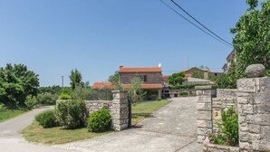 Ein Gebäude mit Steinsäulen und einem gepflasterten Weg, der zu einem Haus mit roten Ziegeln führt.