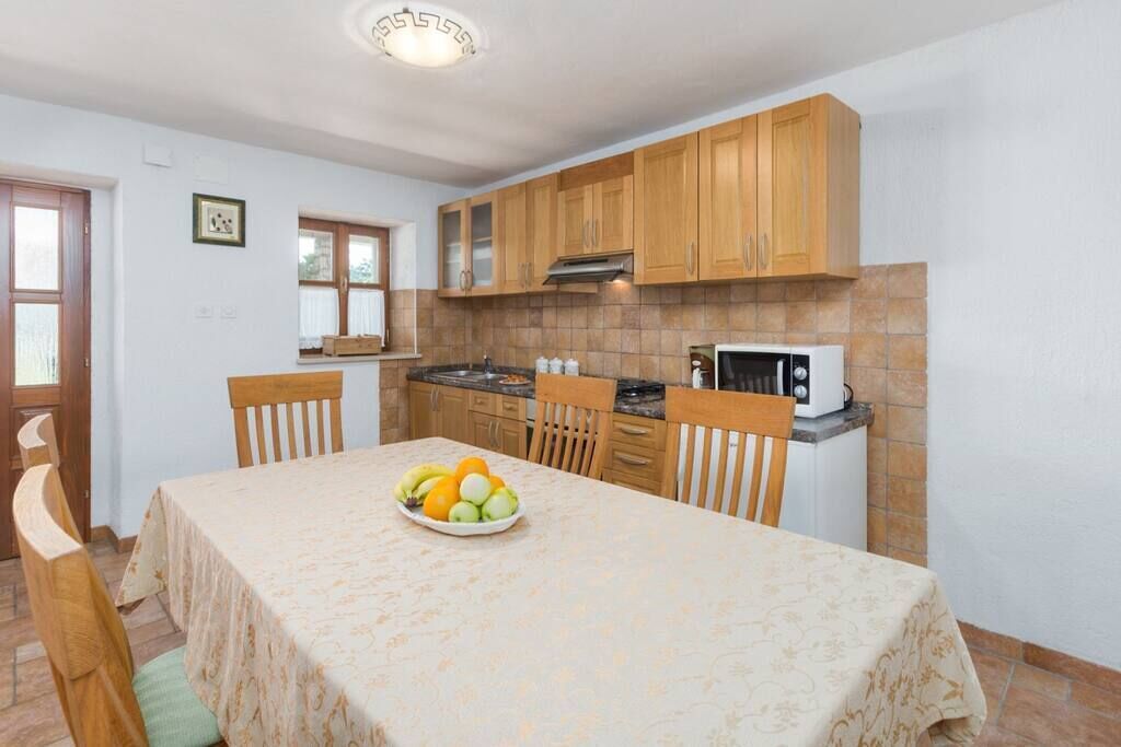 A kitchen with wooden cabinets, a microwave, and a fruit bowl on the table.