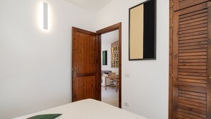 Un dormitorio con cama, una puerta de madera y un estante en la pared con botellas.