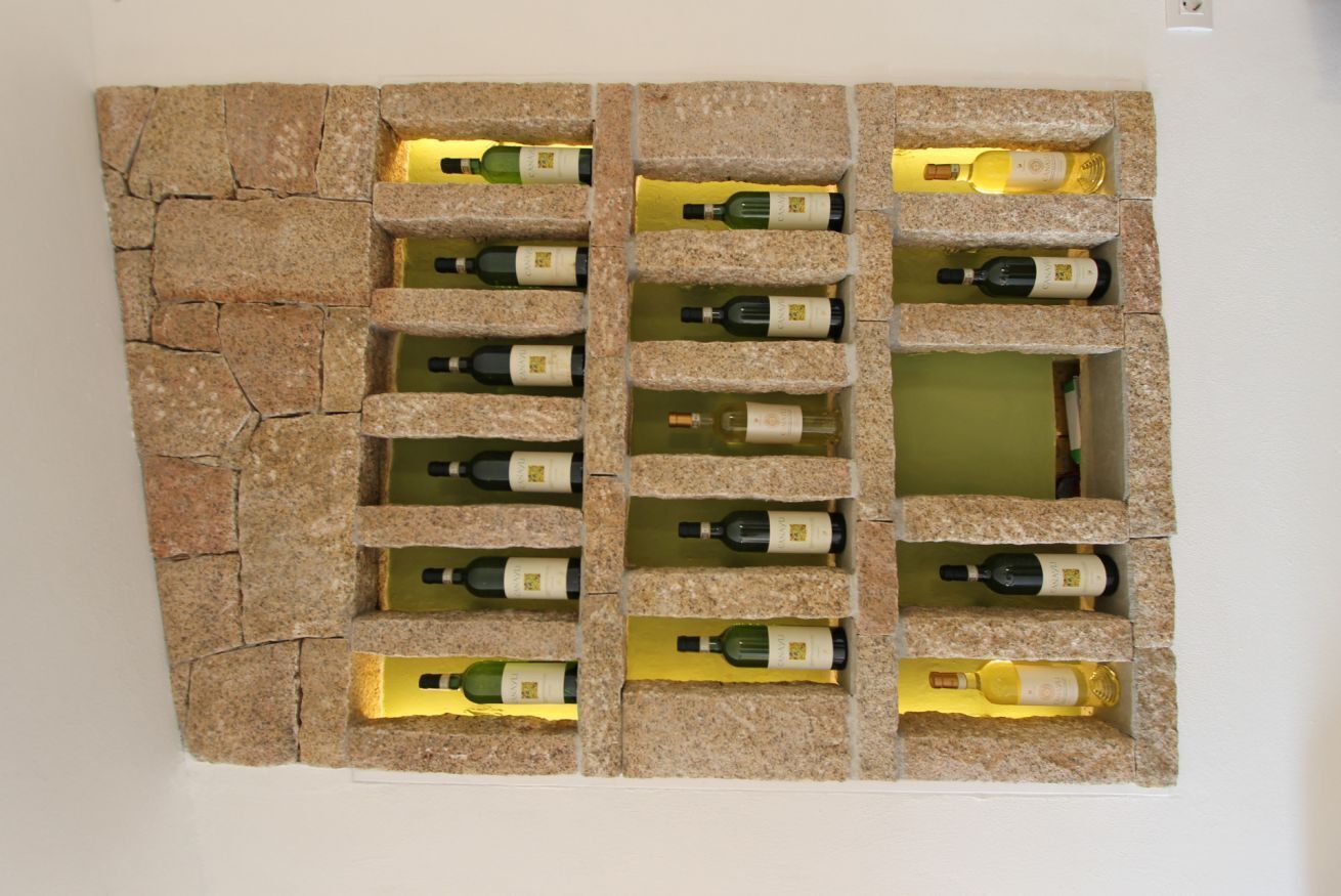 Un mur orné d’un motif imitant la pierre et doté de plusieurs compartiments, chacun contenant une bouteille.