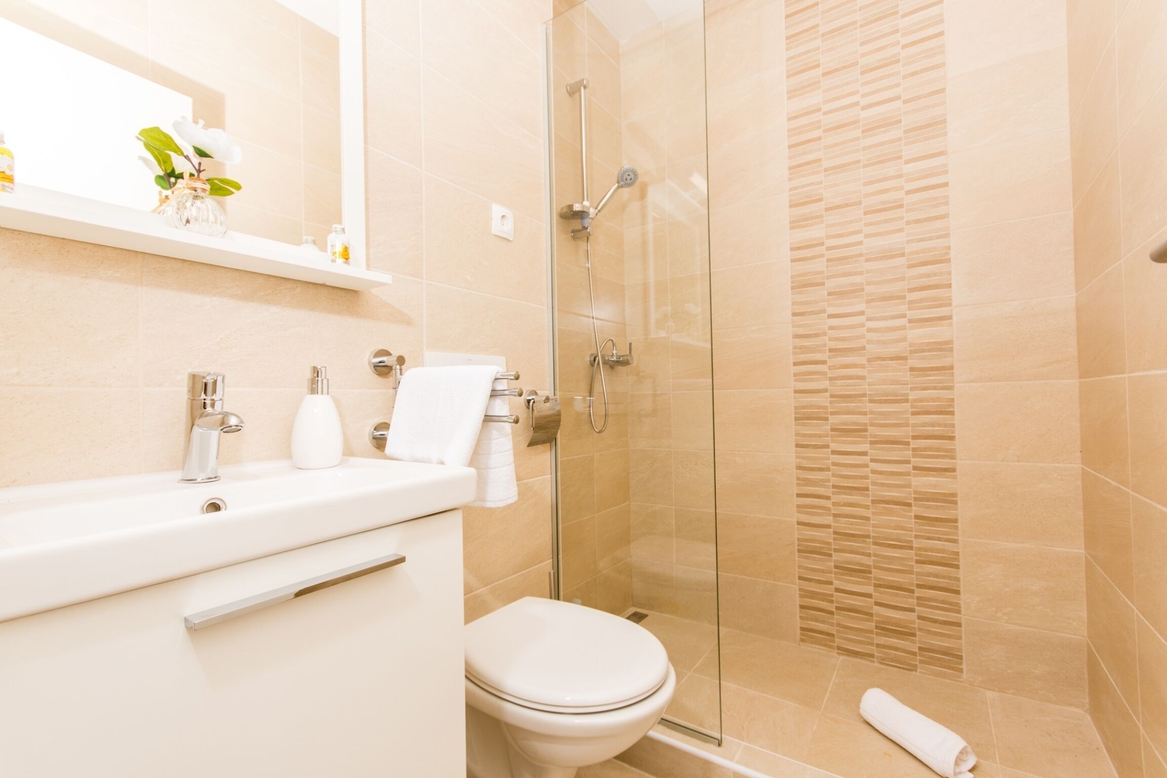A modern bathroom with a glass shower enclosure, a white sink, and a toilet.