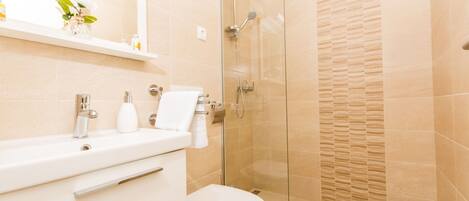 A modern bathroom with a glass shower enclosure, a white sink, and a toilet.