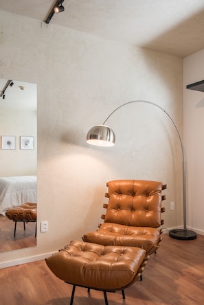 A room with a large mirror, a brown leather chair, and a floor lamp.