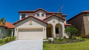 A two-story house with a beige facade, a red-tiled roof, and a garage. - Veranda Palms IHR 1004 (Kissimmee)