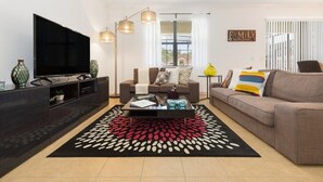 A modern living room with a flat-screen TV, a sofa, a coffee table, and a patterned rug. - Veranda Palms IHR 1004 (Kissimmee)