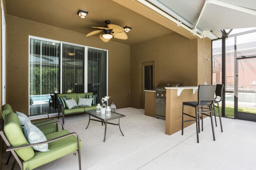 A covered patio area with a green sofa, a small table, and a bar area.