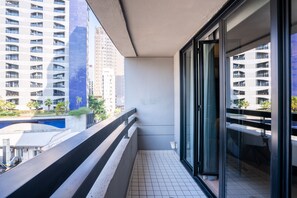 A balcony with a view of high-rise buildings, a tiled floor, and a glass door. - Cyclinn Cidade Jardim (São Paulo)