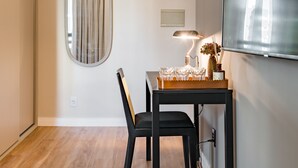 Uma sala de jantar com uma mesa de madeira, cadeiras, um abajur e um espelho na parede.