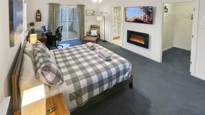 Hotelkamer met een bed, een bureau, een stoel, een televisie, een open haard en een plafondventilator.