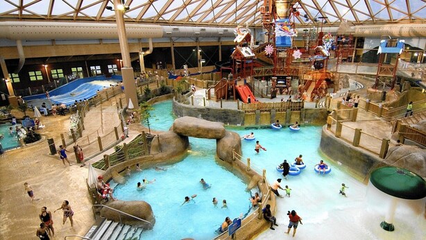 Een overdekt waterpark met diverse zwembaden, glijbanen en waterattracties.