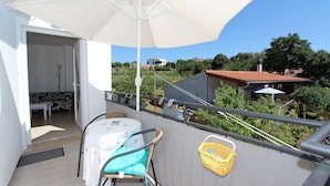 A balcony with a table, chairs, a white umbrella, and a yellow basket. - Apartment Diego & Fabio (Rovinj)