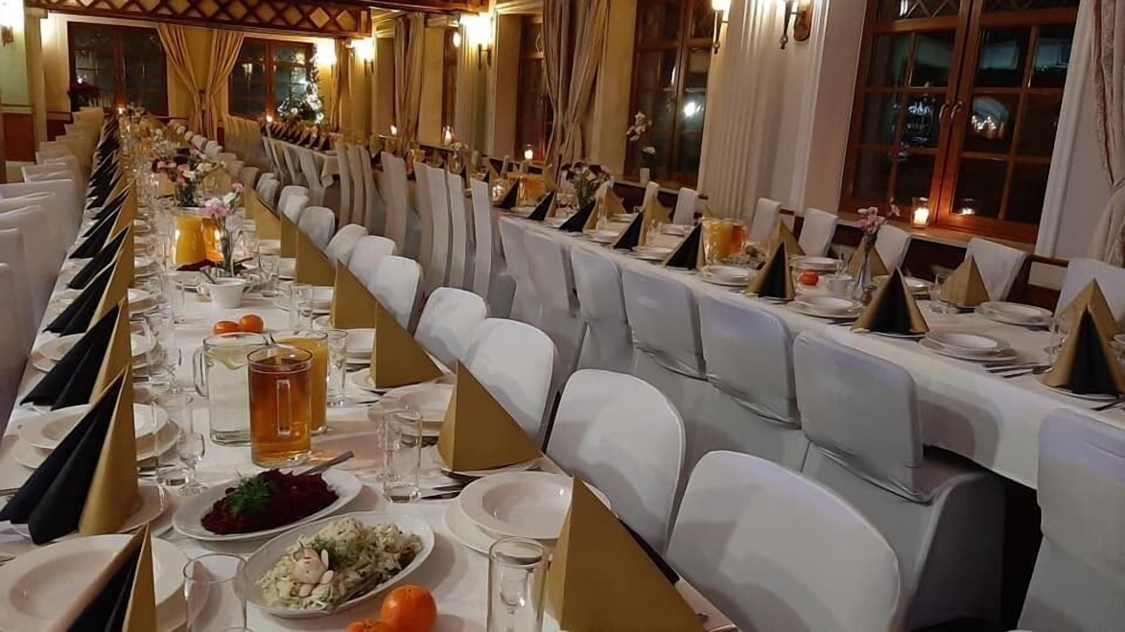 A long banquet table set with white chairs, glassware, and plates, likely for a formal event.