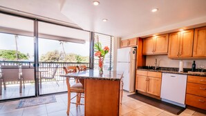 Una cocina moderna con armarios de madera, una isla integrada y un amplio ventanal corredero que da a un balcón.