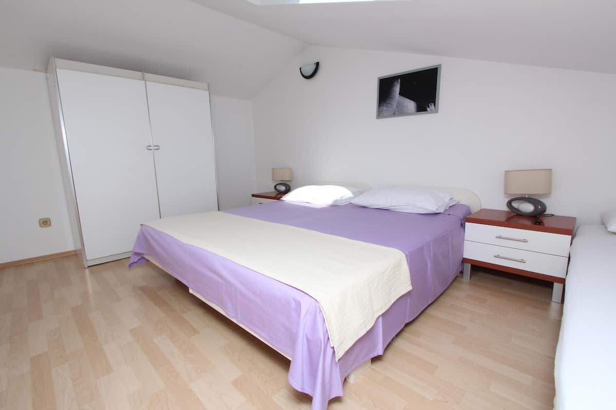 A bedroom with a bed, bedside tables, a wardrobe, and a small wall-mounted picture.