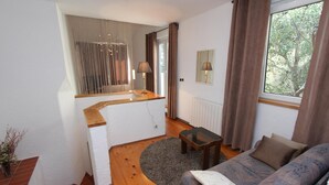 Un salon avec un canapé, une petite table, un miroir et une fenêtre avec des rideaux.