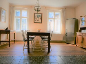 A dining area with a table and chairs, a chandelier, a refrigerator, and a window with curtains. - Large holiday home for families and groups.
With yoga/playroom and garden (Janowice Wielkie)