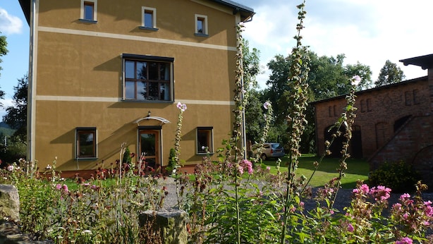 A multi-story building with a flat roof, a central entrance, and multiple windows. - Large holiday home for families and groups.
With yoga/playroom and garden (Janowice Wielkie)