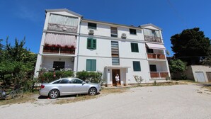A multi-story building with balconies, a car parked in front, and a clear blue sky. - Apartments Paris (Rovinj)