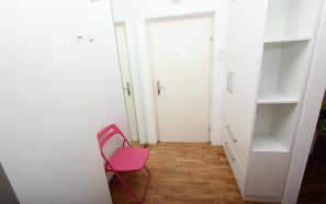 Stylish hallway with a door, chair, and shelving unit.