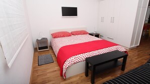 A bedroom with a bed, bedside table, lamp, wardrobe, and a bench. - Apartments Paris (Rovinj)