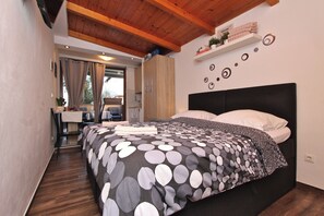 Un dormitorio con una cama, techo de madera, un escritorio y una ventana.