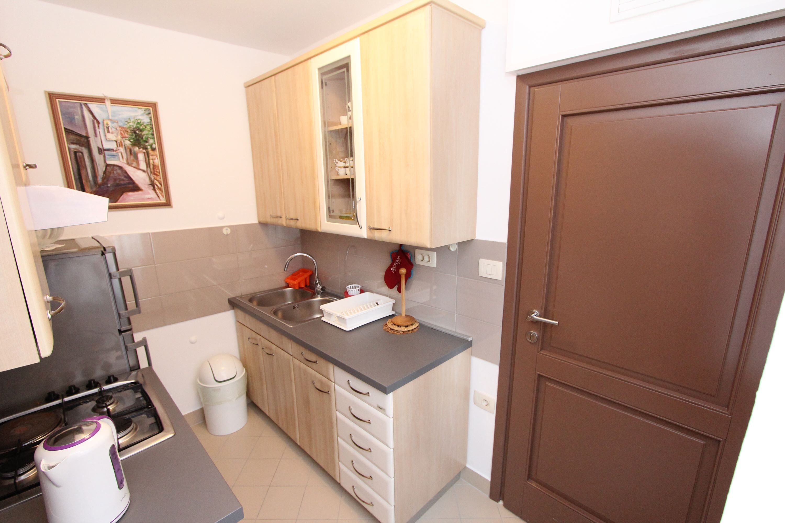 A compact kitchen with a gas stove, a sink, and wooden cabinets.