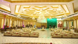 A spacious banquet hall with high ceilings, chandeliers, and ornate golden detailing.