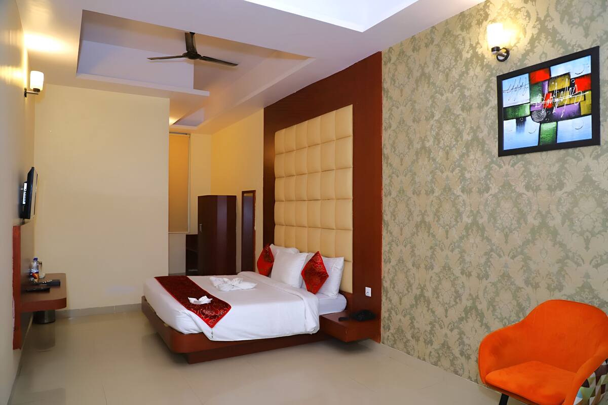 A hotel room with a bed, a chair, a TV, and a ceiling fan.