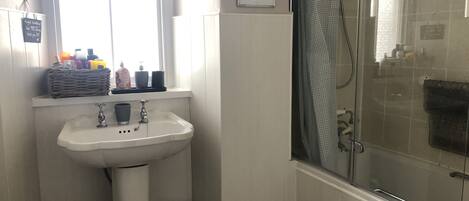 Un bagno con lavandino, doccia e finestra.