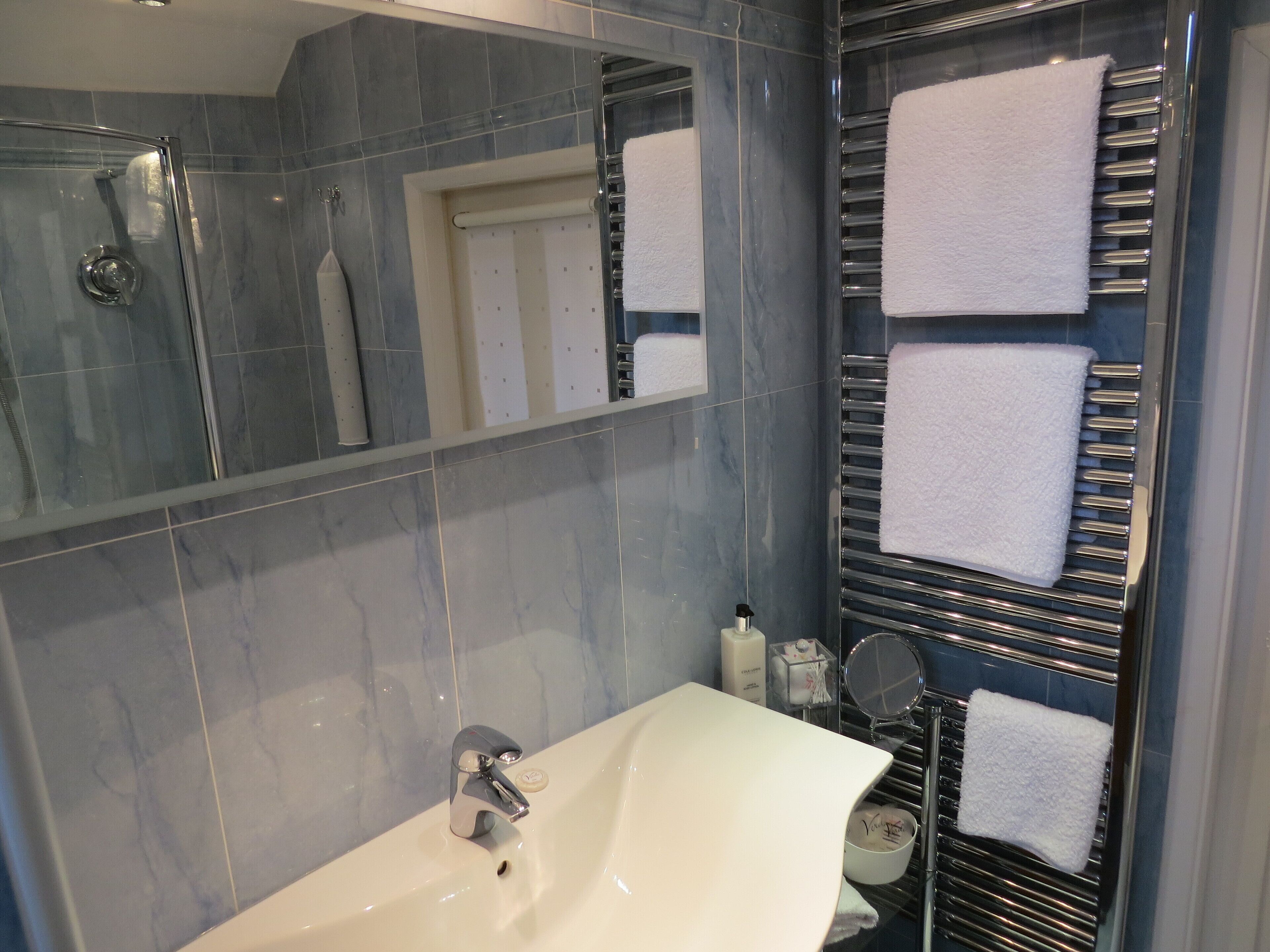 Un baño con lavabo, espejo y perchero para toallas.