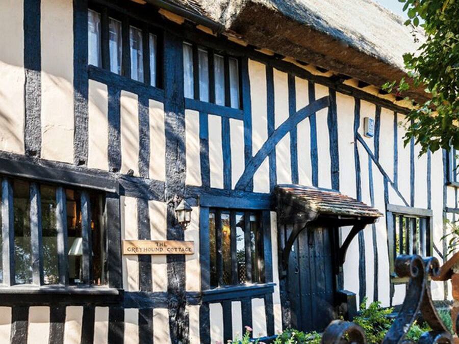 A traditional half-timbered building with a sign reading "The Greyhound Cottage."