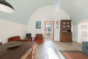 Un ampio soggiorno con un tavolo da pranzo in legno, due poltrone rosse, una televisione e un mobile.
