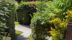 A stone pathway leading through a garden with neatly trimmed hedges and a wooden fence. - Parada Cottage@Mineshop Holiday Cottages, a woodland stroll to Crackington Haven (Bude)