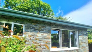A stone house with a large window and a patio area. - Parada Cottage@Mineshop Holiday Cottages, a woodland stroll to Crackington Haven (Bude)