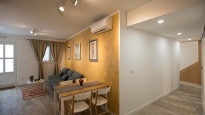 A modern living room with a dining area, a sofa, and a staircase. - Apartment Dam (Dubrovnik)