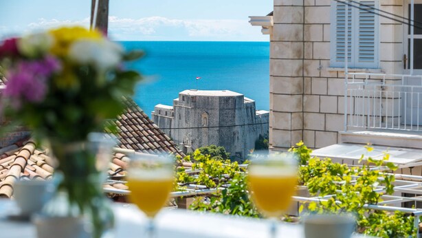 Una mesa con bebidas y vistas al mar y un edificio en la costa.