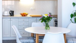 Una cocina moderna con armarios blancos, una mesa redonda con sillas y un jarrón con flores sobre la mesa.