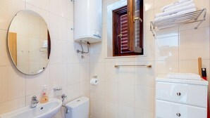 Un baño moderno con lavamanos, inodoro y toallero con toallas dobladas.