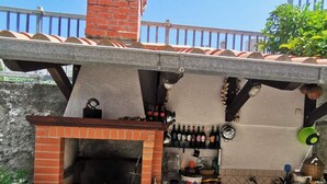 Cocina exterior con horno de ladrillo, barra con botellas y salpicadero de azulejos.