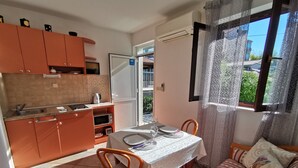 Cocina compacta con comedor, sofá y ventana con cortinas de encaje.