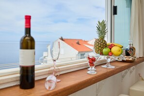 A balcony with a wine bottle, glasses, and a fruit bowl. - Bahari Apartment (Dubrovnik)