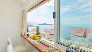 Un balcon avec une table dress ée pour un repas, une vue sur la mer et un paysage urbain en arrière-plan.