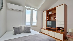 Une chambre à coucher avec un lit, une armoire, une télévision et une fenêtre.