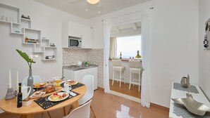 Une cuisine moderne avec des meubles blancs, un four à micro-ondes et un coin repas où une table est dressée pour le petit-déjeuner.