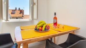 A dining table with a fruit bowl, a bottle, and a glass. - Dominium Old City Suite (Dubrovnik)